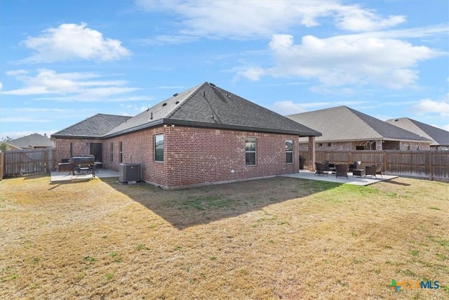 back of house featuring a fenced backyard, a yard, a patio area, central AC, and brick siding