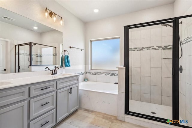 full bathroom with a garden tub, double vanity, visible vents, a sink, and a shower stall