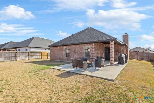 rear view of property featuring a yard, a patio area, brick siding, and a fenced backyard