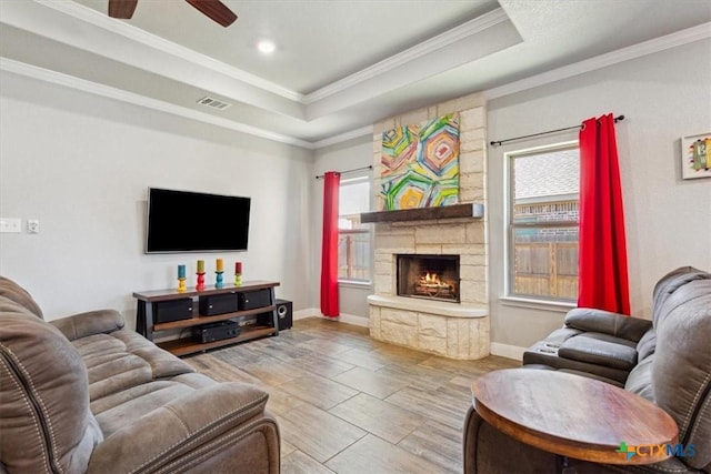 living room featuring ornamental molding, a wealth of natural light, a raised ceiling, and visible vents