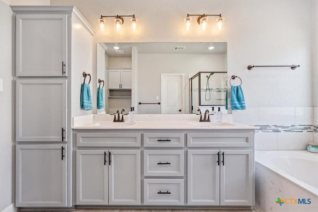 bathroom featuring double vanity, a stall shower, a sink, and visible vents