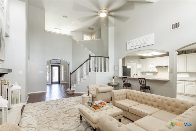 living room with light hardwood / wood-style floors, ceiling fan, and high vaulted ceiling