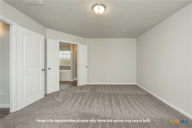 empty room featuring a textured ceiling and dark colored carpet