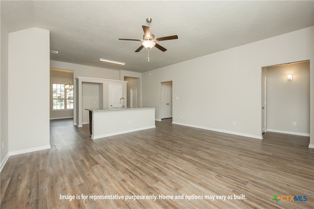 unfurnished living room featuring a textured ceiling, hardwood / wood-style flooring, ceiling fan, and sink