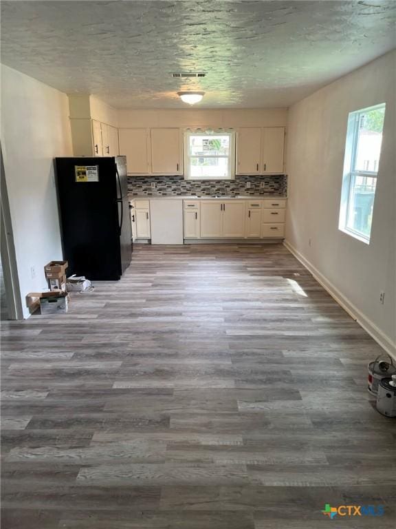 255 Pollard St, Beaumont, TX 77703 - kitchen featuring freestanding refrigerator, white cabinets, wood finished floors, and tasteful backsplash