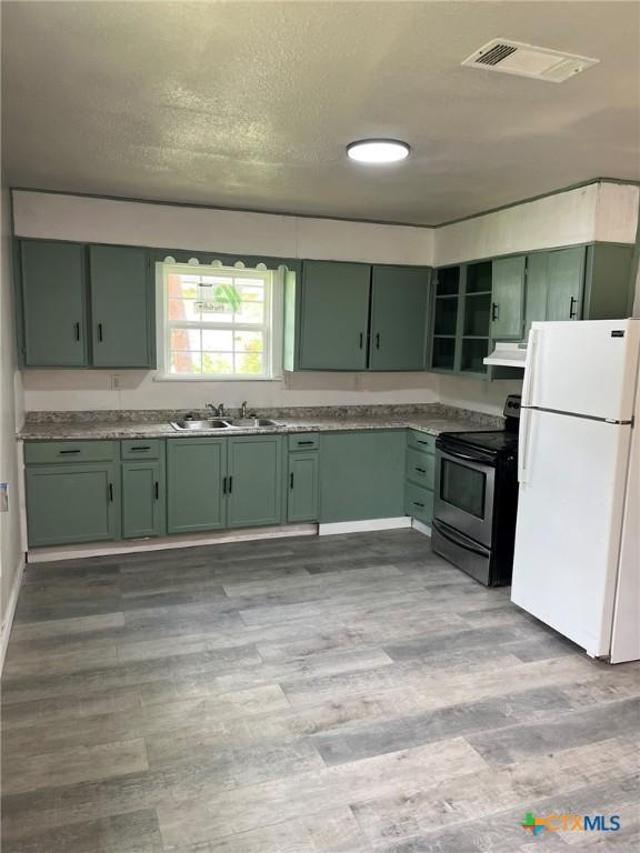 255 Pollard St, Beaumont, TX 77703 - kitchen with green cabinetry, freestanding refrigerator, electric stove, a sink, and a textured ceiling