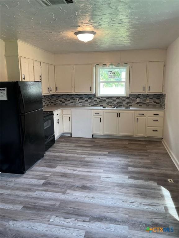 255 Pollard St, Beaumont, TX 77703 - kitchen featuring black appliances, decorative backsplash, light wood-style floors, white cabinets, and light countertops