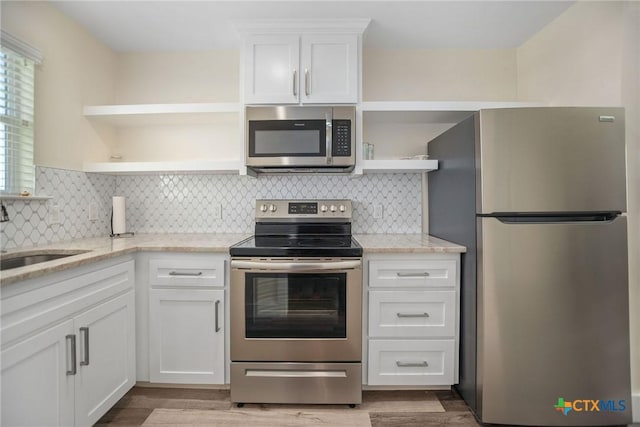 105 N Redfish Retreat Dr, Port Lavaca, TX 77979 - kitchen featuring appliances with stainless steel finishes, open shelves, a sink, white cabinetry, and light wood-style flooring