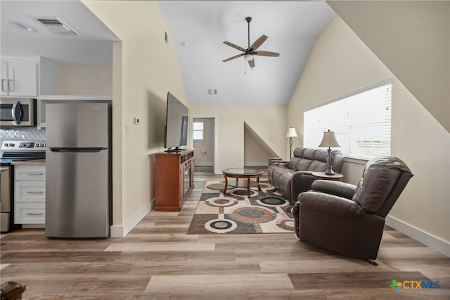 living room featuring light wood-type flooring, ceiling fan, and high vaulted ceiling