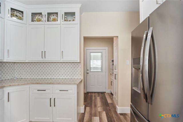 kitchen with white cabinetry, light stone countertops, dark wood-type flooring, stainless steel fridge, and decorative backsplash