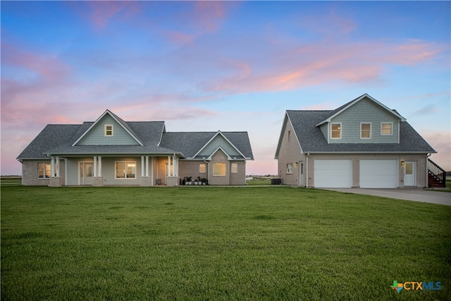 view of front of property featuring a garage, covered porch, and a yard