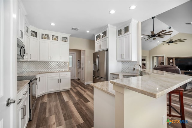 kitchen featuring white cabinetry, kitchen peninsula, appliances with stainless steel finishes, and vaulted ceiling