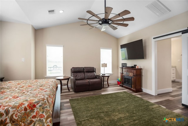 bedroom featuring lofted ceiling, dark hardwood / wood-style floors, ceiling fan, and a barn door