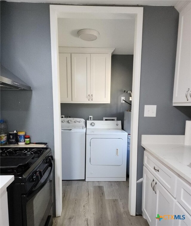 laundry area featuring washer and dryer, light hardwood / wood-style flooring, and cabinets