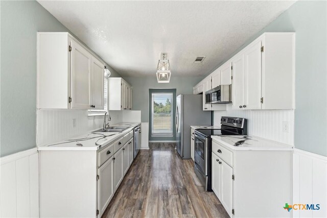 3400 Sally Cir, Kempner, TX 76539 - kitchen with stainless steel appliances, a sink, white cabinetry, light countertops, and wainscoting