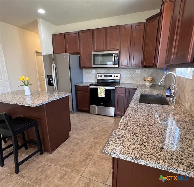 kitchen with a sink, tasteful backsplash, stainless steel appliances, light tile patterned floors, and light stone countertops