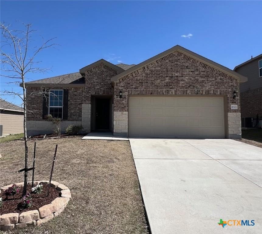 single story home with brick siding, an attached garage, and concrete driveway