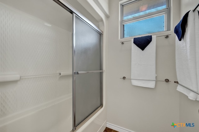 bathroom featuring combined bath / shower with glass door