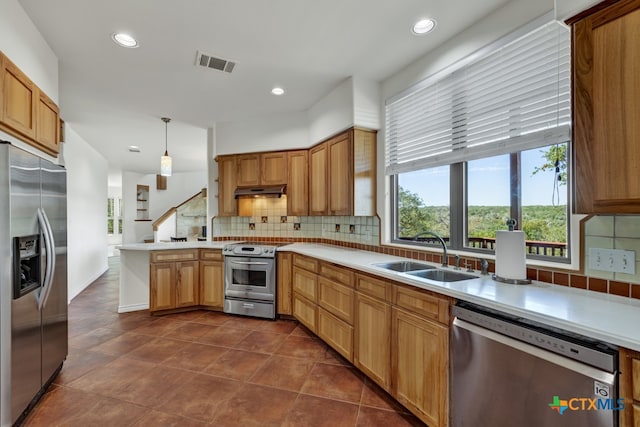 kitchen featuring stainless steel appliances, kitchen peninsula, decorative backsplash, hanging light fixtures, and sink