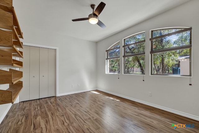 unfurnished bedroom featuring hardwood / wood-style flooring, ceiling fan, and a closet