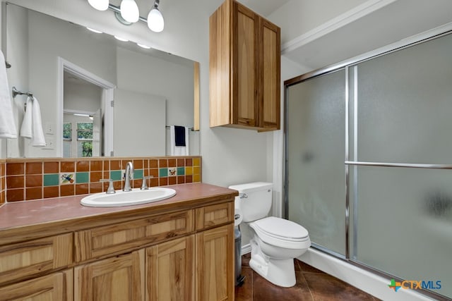 bathroom with backsplash, vanity, tile patterned flooring, toilet, and a shower with shower door