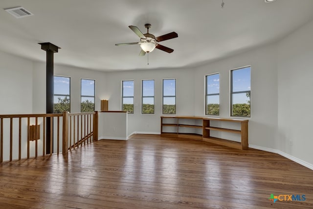 empty room featuring ceiling fan, dark hardwood / wood-style floors, and a healthy amount of sunlight