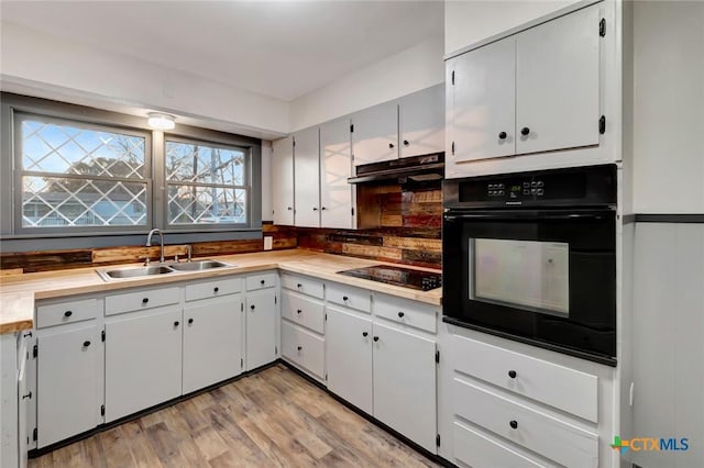 2901 Lone Tree Rd, Victoria, TX 77901 - kitchen with black appliances, under cabinet range hood, light wood-style flooring, white cabinets, and light countertops