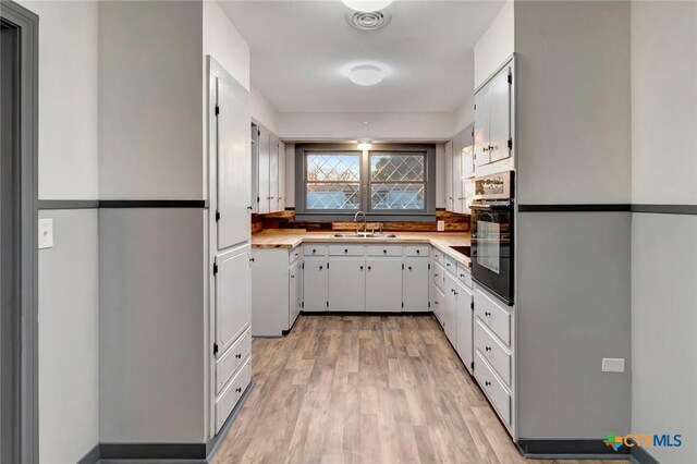 2901 Lone Tree Rd, Victoria, TX 77901 - kitchen with oven, light countertops, light wood finished floors, and white cabinets