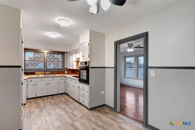 2901 Lone Tree Rd, Victoria, TX 77901 - kitchen featuring oven, a ceiling fan, freestanding refrigerator, light wood-style floors, and wainscoting