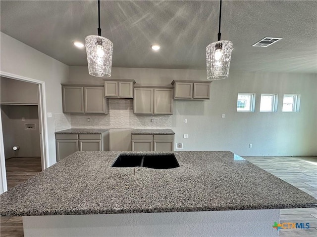 2591 Cedar Glen Dr, Belton, TX 76513 - kitchen with dark stone counters, wood finished floors, gray cabinets, backsplash, and recessed lighting