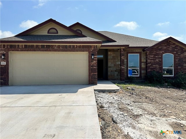 2591 Cedar Glen Dr, Belton, TX 76513 - view of front of house with an attached garage, a shingled roof, driveway, and brick siding