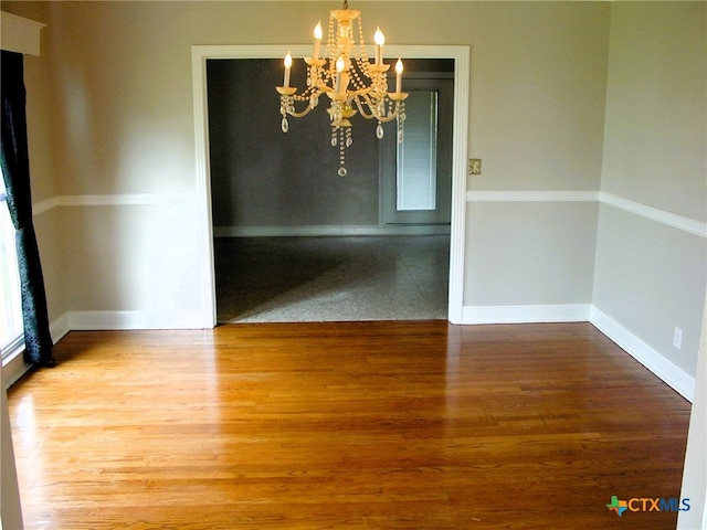 unfurnished dining area featuring wood-type flooring and a notable chandelier