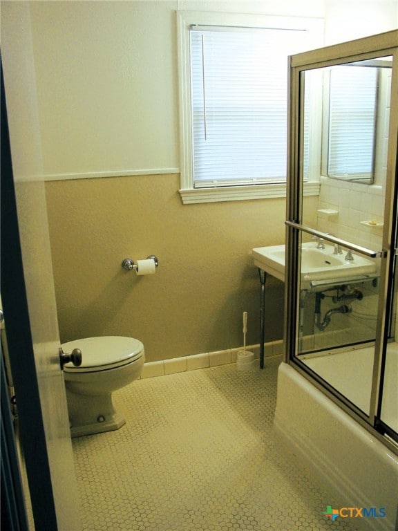 bathroom featuring shower / bath combination with glass door, tile patterned flooring, and toilet