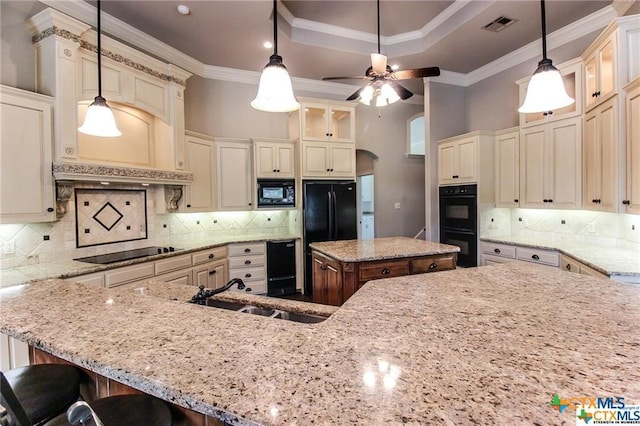 kitchen featuring pendant lighting, a center island, black appliances, sink, and light stone counters