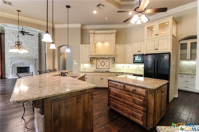 kitchen featuring a kitchen bar, dark wood-type flooring, crown molding, black appliances, and a large island