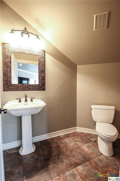 bathroom with lofted ceiling and toilet