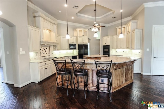 kitchen with light stone countertops, a center island, black appliances, and dark hardwood / wood-style floors