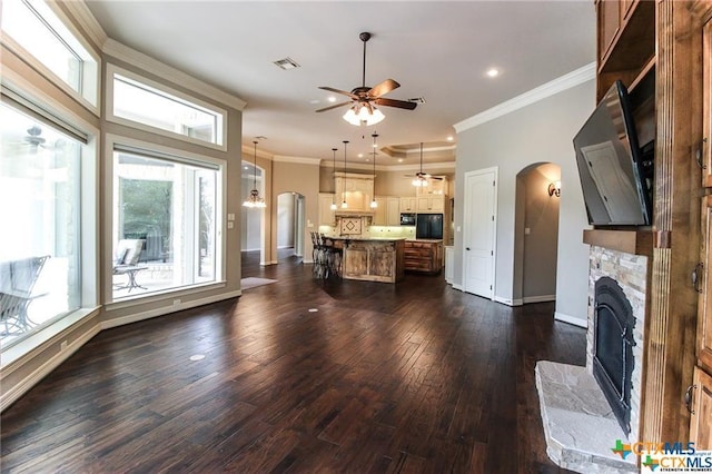 unfurnished living room with ceiling fan, dark hardwood / wood-style flooring, ornamental molding, and a fireplace