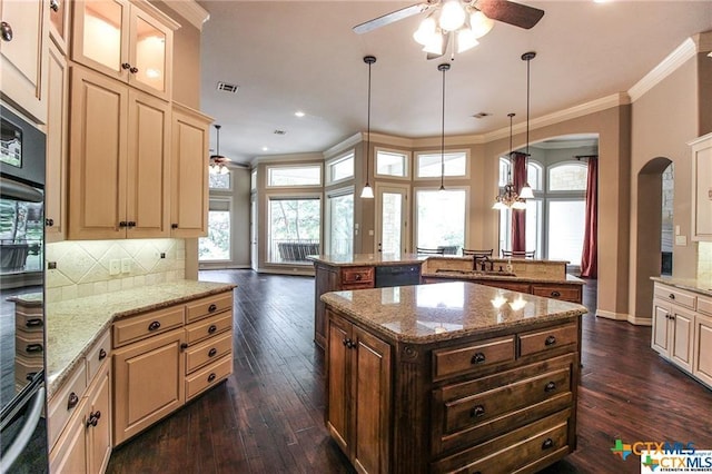 kitchen featuring tasteful backsplash, light stone counters, dark wood-type flooring, crown molding, and a kitchen island