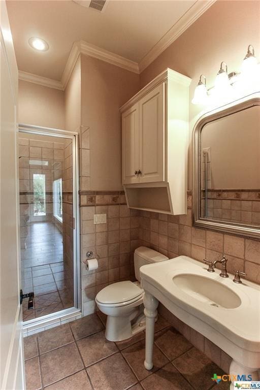 bathroom featuring tile patterned flooring, toilet, ornamental molding, and tile walls