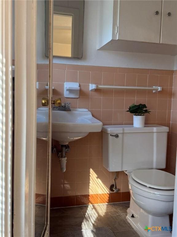 bathroom featuring tile patterned flooring, sink, tile walls, and toilet