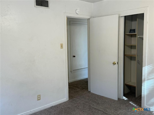 unfurnished bedroom with dark colored carpet and a closet