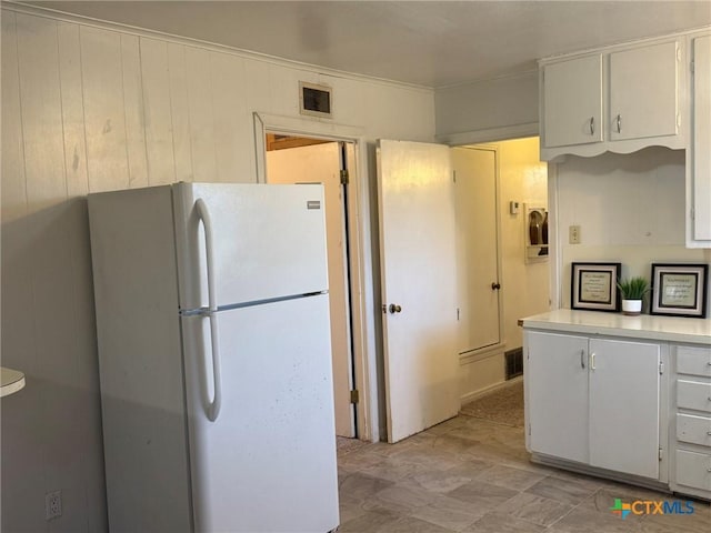 kitchen with white refrigerator and white cabinetry