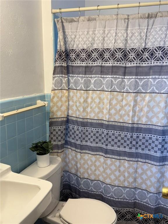 bathroom featuring tile walls, sink, and toilet