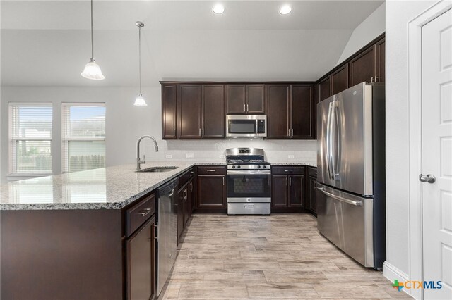 232 Gaida Loop, Georgetown, TX 78628 - kitchen with stainless steel appliances, a sink, lofted ceiling, dark brown cabinets, and light stone counters
