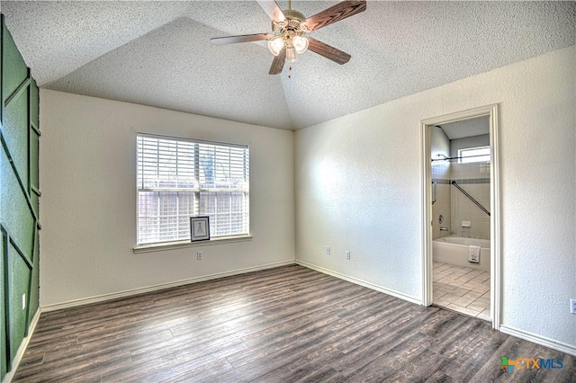 unfurnished bedroom featuring lofted ceiling, wood finished floors, a textured wall, and a textured ceiling