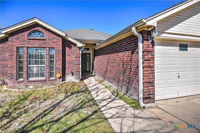 view of exterior entry featuring brick siding and a garage