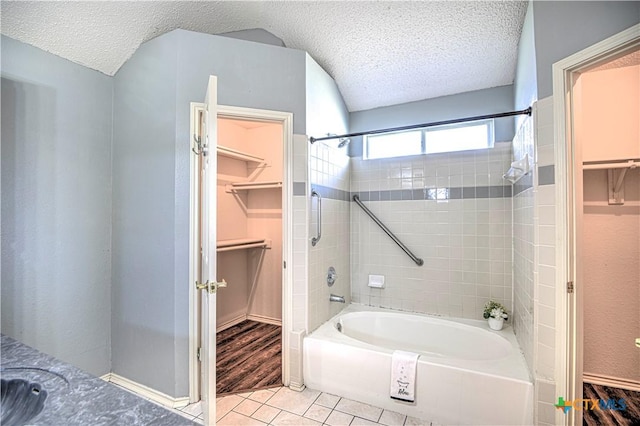 full bath with tile patterned flooring, a walk in closet, a textured ceiling, and shower / tub combination