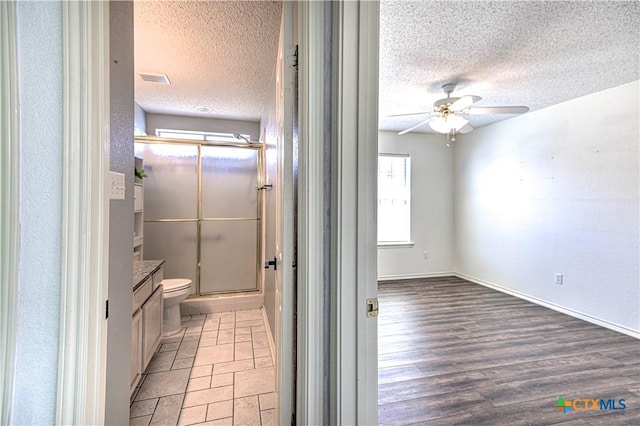 full bathroom featuring a textured ceiling, a stall shower, toilet, and ceiling fan