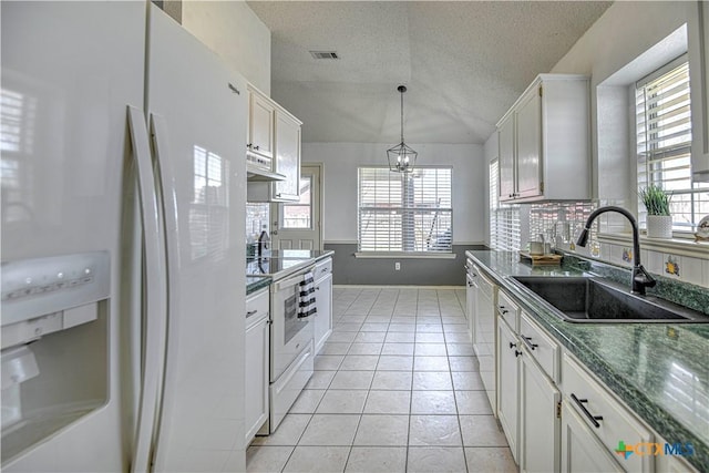 kitchen featuring white appliances, light tile patterned floors, visible vents, a sink, and vaulted ceiling